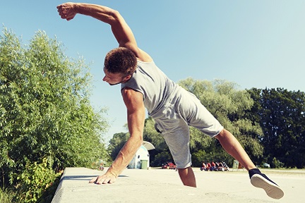 Ein Man überwindet eine Mauer, im Parkourstiel 