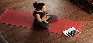 Frau mit Laptop beim Online-Yoga