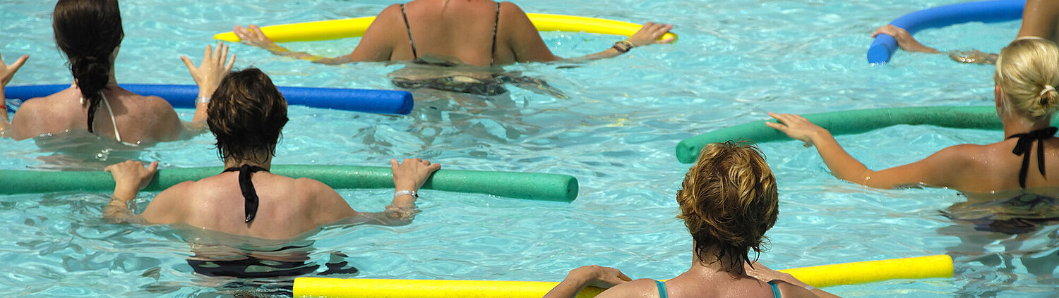 [Translate to Englisch:] Personen stehen im Wasser und haben vor sich eine Pool Nudel