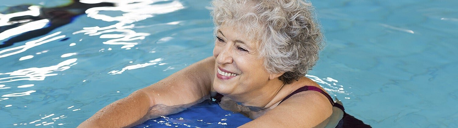 Frau schwimmt mit Brett und lächelt