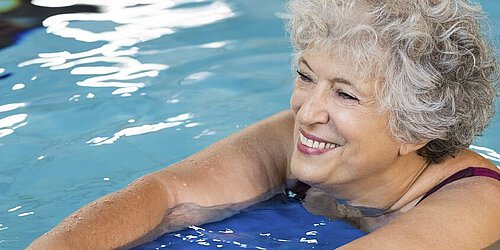 Frau schwimmt mit Brett und lächelt