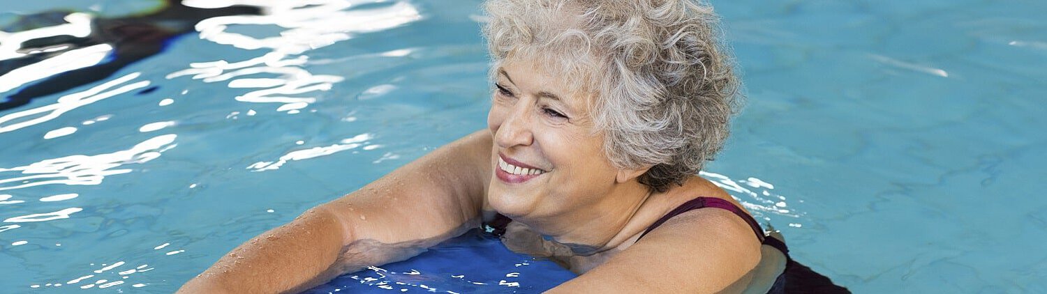 Frau schwimmt mit Brett und lächelt