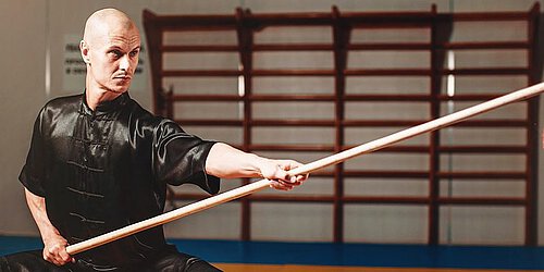 Mann hält Kung Fu Stab hoch
