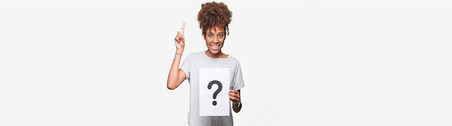 A woman is raising her hand and holding a question mark sign in the other hand.