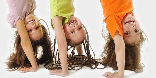 Foto von drei Kinder die ein Handstand amchen